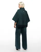 Pantalón de denim verde inglés con corte sastrero de pierna ancha, tiro alto y pretina cruzada.