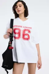 Remera blanca con estampado de texto 'Leisure League' y el número 96 en rojo.