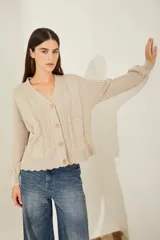 Cardigan tejido color beige con cuello en V, cierre con botones, mangas largas con puños acanalados y bordados con motivos florales.