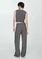 Pantalón gris con finas rayas verticales blancas, de corte wide leg, con trabillas, pinzas y bolsillos laterales.