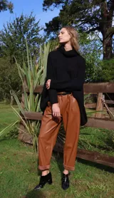 Pantalón babucha verde de cuerina con bolsillos laterales y cinturón fino marrón.