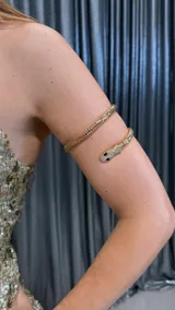 Brazalete dorado con forma de serpiente con incrustaciones de strass y ojos negros.