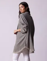 Camisa de jean celeste, marca Hester & Orchand, de corte oversize con cuello con solapa, escote en V y abertura central con botones. Delantera con bolsillos aplicados, mangas largas regulables con presilla y botón, y ruedo desflecado.
