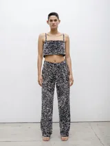 Pantalón largo de vestir negro con lentejuelas plateadas, de corte recto y tiro alto.