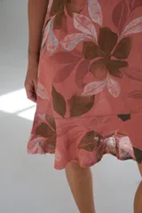 Vestido corto color salmón con estampado de hojas en tonos marrones y grises. Sin mangas y con ruedo con volados.