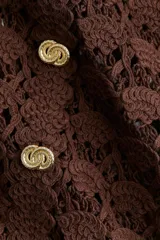 Vestido corto marrón de crochet con cuello camisero, botones dorados y mangas largas.
