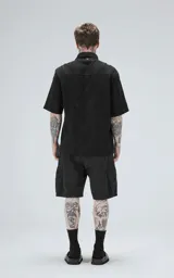 Camisa negra de manga corta con textura floral en relieve y cuello clásico.