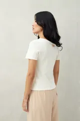 Top tejido azul marino de silueta ajustada con diseño minimalista y escote asimétrico, adornado con pequeños botones metálicos.