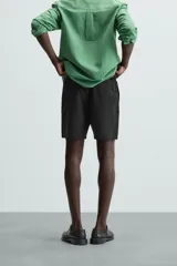 Bermuda de algodón color marrón oscuro, de corte regular fit, con cintura elástica ajustable mediante cordón. Presenta bolsillos laterales y un bolsillo trasero de vivo.