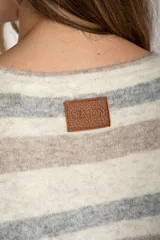 Sweater color crema con rayas horizontales en tonos marrón, bordeaux y beige.