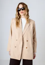 Blazer color beige con doble botonadura, solapas de muesca y corte holgado.