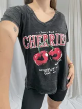 Remera negra con efecto gastado, cuello en V y estampado de cerezas con la frase "Cherry Pain".