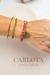 Pulsera dorada de acero quirúrgico con doble cadena, una de eslabones y otra con cuentas rosas. Dije en forma de corazón con ojo grabado y mini cristal.