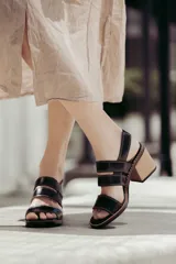 Sandalias de cuero color beige y marrón, con tiras anchas cruzadas en el empeine, puntera descubierta y tacón cuadrado de madera.