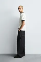 Pantalón de jean negro de corte amplio, con bolsillos delanteros y traseros, presilla portaherramientas en la pierna derecha y costuras a contratono.