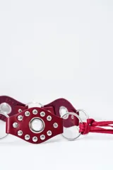 Cinto de cuero color bordó con tachas plateadas y argollas metálicas.