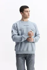 Buzo blanco de algodón con cuello redondo, puños y bolsillos laterales. Presenta un estampado en la espalda con cuatro imágenes de plantas en tonos sepia y texto.