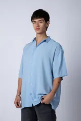 Camisa celeste de manga corta con cuello clásico y calce oversize.