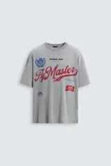 Camiseta gris con cuello redondo y manga corta. Presenta estampados, bordados y parches frontales combinados a contraste. Tiene un efecto lavado.