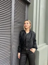 Bomber negra de corte cropped, con cierre frontal y cuello redondo, ideal para completar looks urbanos.
