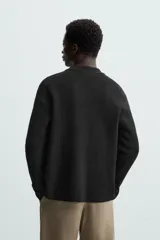 Cárdigan negro de lana y algodón, corte regular fit, con cuello solapa, manga larga, terminaciones en rib y cierre frontal con botones.