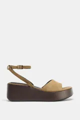Sandalia color beige con plataforma de madera, tira ancha delantera y cierre con hebilla al tobillo.