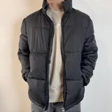 Campera puffer negra con cierre frontal y cuello alto.