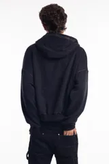 Campera negra con cierre frontal, capucha y costuras a la vista en color blanco. Tiene remaches metálicos y un pequeño bordado en el pecho.