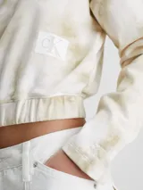 Buzo corto de algodón color blanco con estampado tie dye en tonos beige, cuello redondo, mangas largas, bajo elástico y parche con el monograma de Calvin Klein en el pecho.