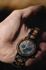 Reloj de pulsera Chenaut Aurum para hombre, con caja de acero inoxidable negra y esfera de madera de zebrano. La malla es de acero inoxidable negra con detalles en madera de bambú. Tiene cronógrafo, indicador de 24 horas y fechador.