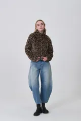 Campera corta de tejido peluche (corderito) con cierre frontal y cuello camisero. Presenta un estampado animal print de cebra o tigre en tonos marrón claro y negro.