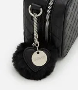 Cartera negra tipo camera bag con textura en relieve, correa de mano, asa desmontable y pompón colgante.