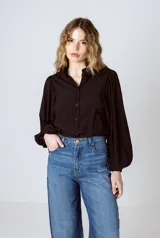 Camisa negra con cuello mao, abotonada al frente y mangas largas abullonadas con puños elásticos.