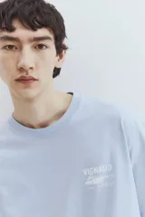 Remera celeste de algodón con cuello redondo y estampado frontal con la palabra "VIGNAUD" y un dibujo de una lancha.