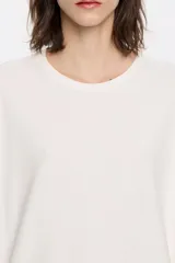 Remera color blanco hueso de corte cuadrado, con cuello redondo y mangas cortas amplias.