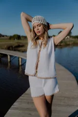 Conjunto tejido de algodón color celeste con terminaciones en marrón. Incluye un top sin mangas con botones y un short de tiro alto.