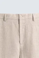 Pantalón de vestir color beige claro, confeccionado en lino, de corte recto, con bolsillos laterales y traseros.