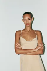 Vestido largo color beige de tejido de punto, con escote drapeado y tirantes finos ajustables. Espalda descubierta con escote drapeado y tira con gancho metálico.