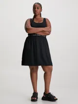 Vestido corto negro de Calvin Klein Jeans con corte evasé, breteles anchos y espalda deportiva. Presenta una banda elástica con el logo de la marca en la cintura.