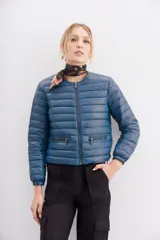 Campera azul de nylon con relleno de pluma, corte holgado a la cintura, cuello redondo y cierre frontal. Tiene bolsillos con cierre y detalle de vivos.