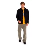 Chaqueta negra de twill de algodón con cierre frontal a presión, bolsillos superiores en el pecho y en la parte inferior, puños elásticos, forro con logo de Caterpillar y bolsillo interior en el pecho.