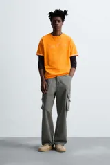 Camiseta naranja de algodón con cuello redondo y manga corta con vuelta. Estampado frontal con la firma del artista Otis Kwame Kye Quaicoe.