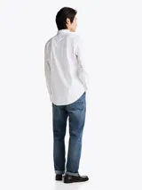 Camisa blanca de corte slim fit, con cuello abotonado, cierre con botones y logo de Tommy Hilfiger bordado en el pecho.
