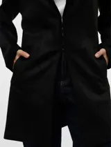 Abrigo negro con cuello de solapa invertida, mangas largas y bolsillos laterales.