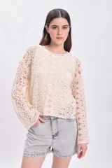 Sweater de crochet color crudo con mangas largas acampanadas.