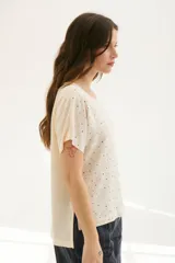 Blusa color crema con estampado de lunares negros, cuello redondo y mangas cortas.