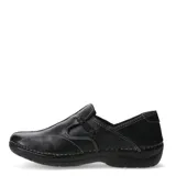 Zapato casual de mujer color marrón claro, estilo mocasín con costuras decorativas en la puntera y elástico negro cruzado en el empeine. Posee suela negra gruesa y ergonómica.