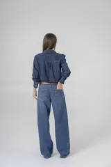 Pantalón de jean azul, corte recto y extra largo, con aplique de denim y ojalillo en una pierna.