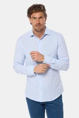 Camisa de manga larga, color celeste con finas rayas blancas, confeccionada en una mezcla de lino y algodón. Presenta un corte slim fit y no tiene bolsillo.