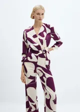 Mono largo estampado en tonos crema y morado, con diseño cruzado, cuello pico con solapa, manga larga abotonada, cinturón desmontable y forro interior.